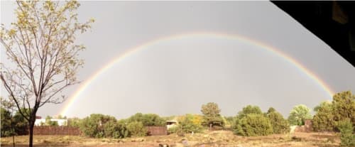 A rainbow above adobe buildings and green fields